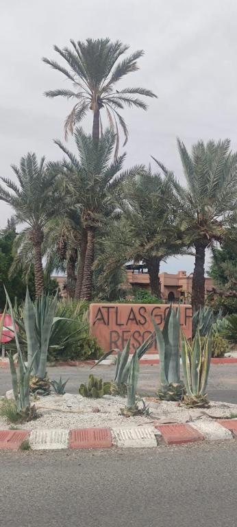 a sign in front of palm trees in a street at Atlas Golf Resort - Marrakech palmeraie a 6 k m du centre in Marrakesh
