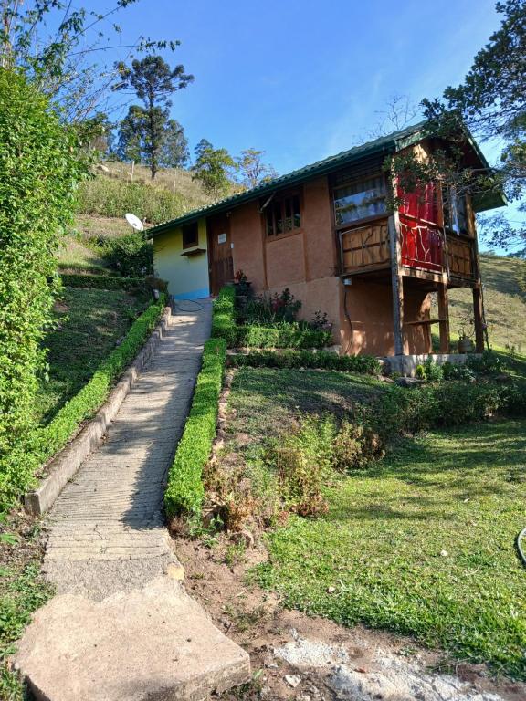 a house on a hill with a path in front of it at Pau a Pique Chalé in Bocaina de Minas