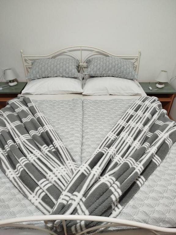 a bed with a white and gray comforter and pillows at Apartman Ivana in Slavonski Brod