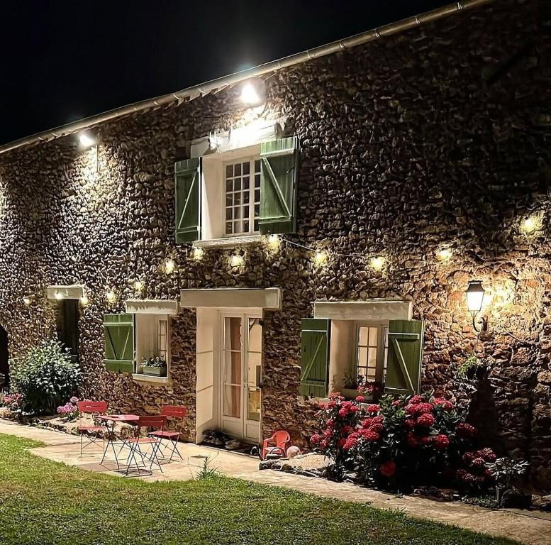 a stone building with lights on it at night at Grande maison avec piscine 13 couchages proche Paris in Rebais