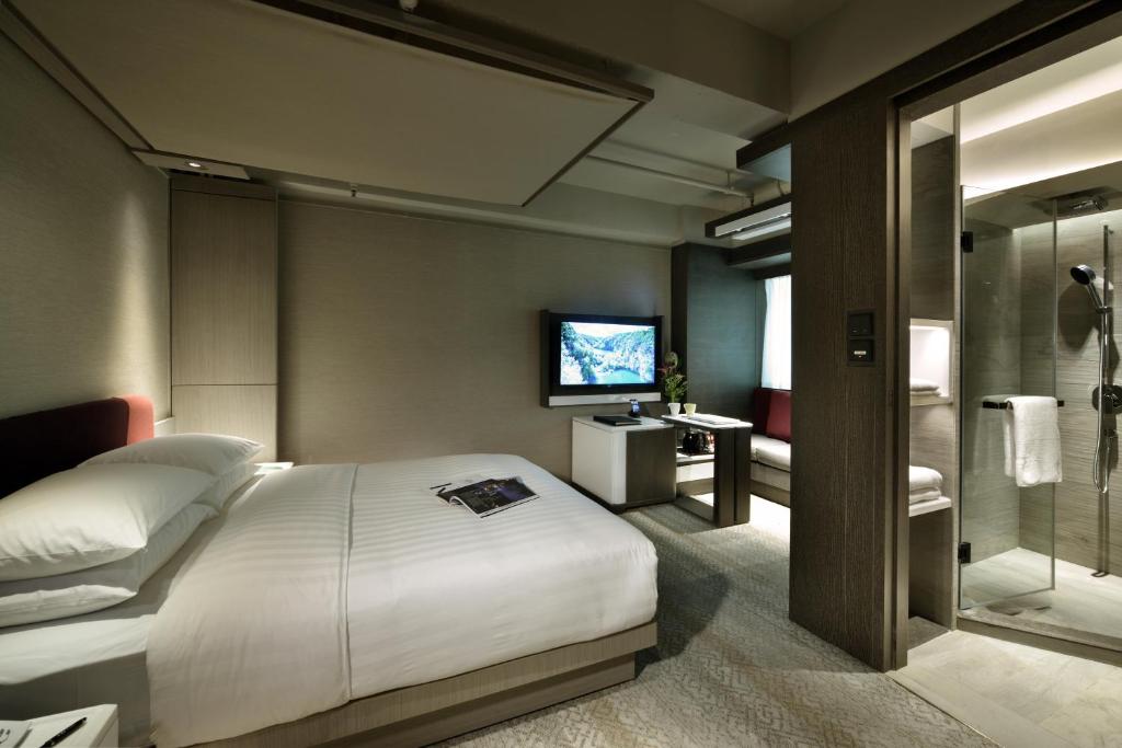 una camera con un grande letto e una televisione di Xi Hotel a Hong Kong