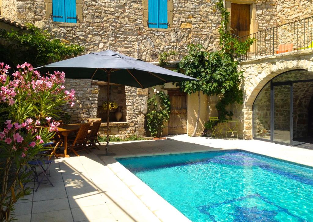 una piscina con sombrilla y sillas y una mesa con en L'Autre Maison, en Saint-Jean-de-Ceyrargues