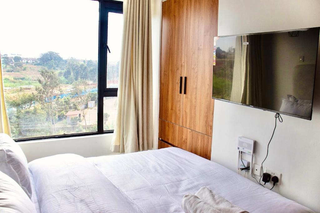 a bedroom with a bed and a large window at Eloura Homes Stanley Studio in Kiambu