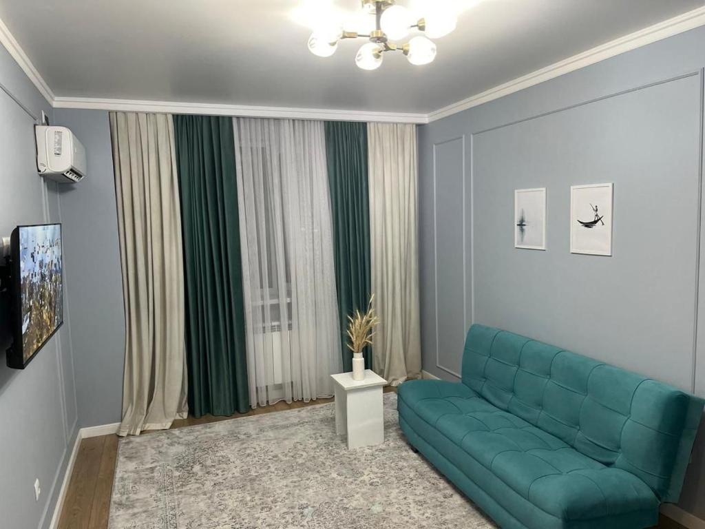 a living room with a blue couch in front of a window at Комфортные апартаменты в ЖК Наурыз парк in Shymkent