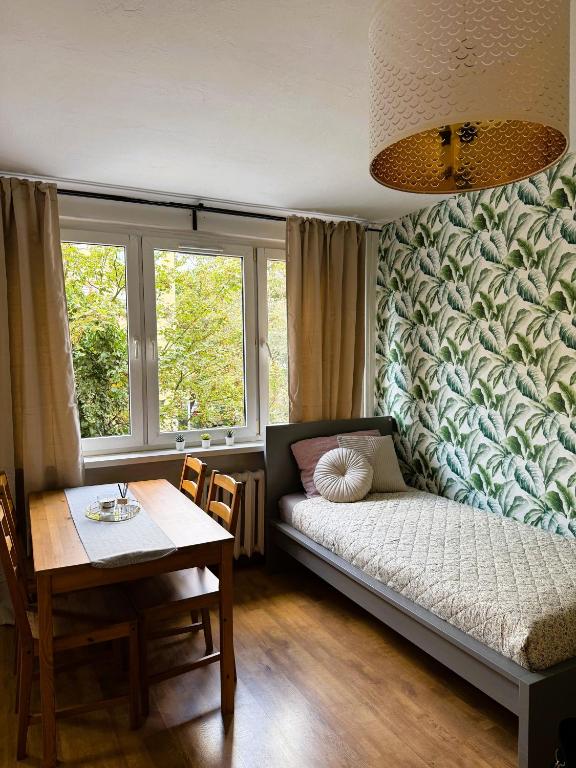 a room with a bed and a table and a window at Justinrent Piekarska in Legnica