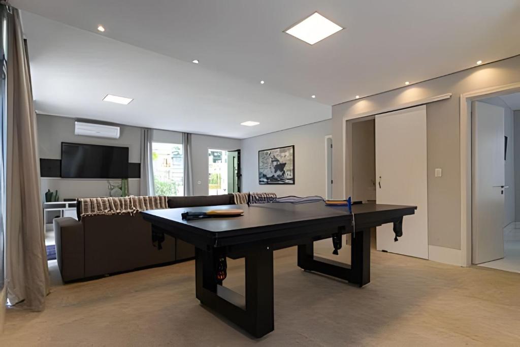 a ping pong table in a living room with a couch at Alto Padrão 5 Stes +1 apoio Piscina quente+Jacuzzi in Praia Guaratuba
