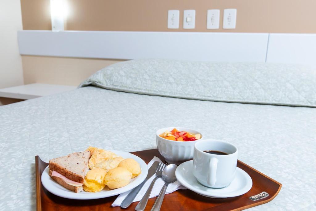 a tray with a plate of food and a cup of coffee at Hotel Suárez São Leopoldo in São Leopoldo