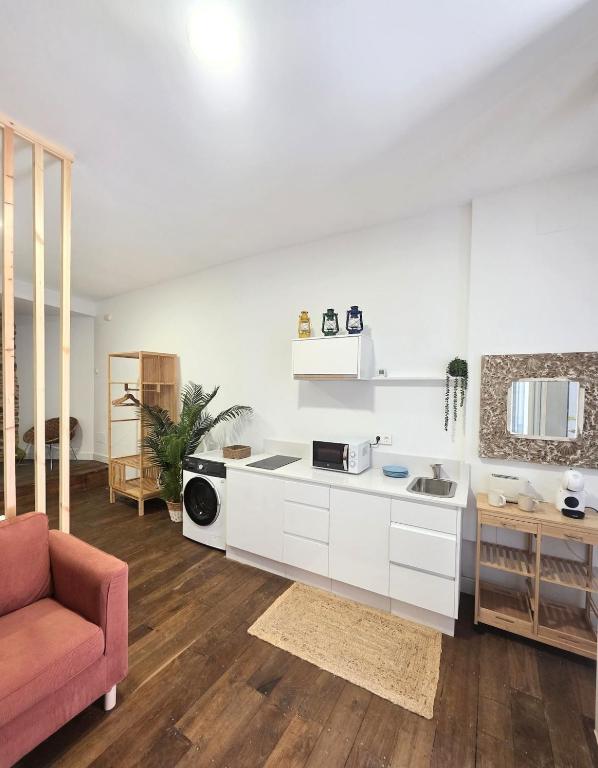 a kitchen with white cabinets and a pink couch at Estudio Casco Histórico Betanzos in Betanzos