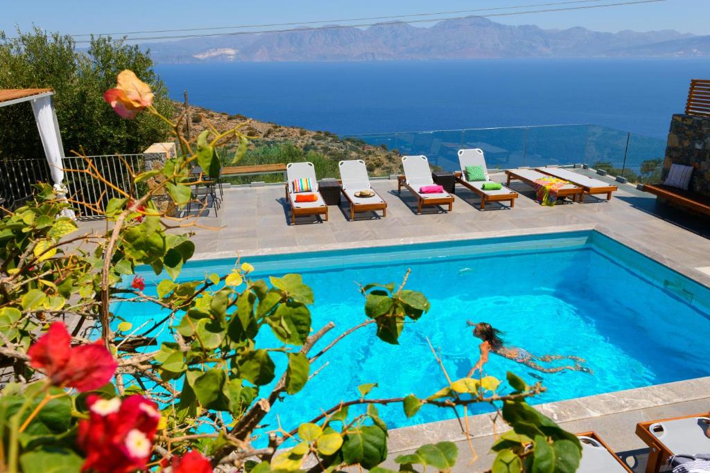 uma piscina com cadeiras e vista para o oceano em Villa Olga em Agios Nikolaos