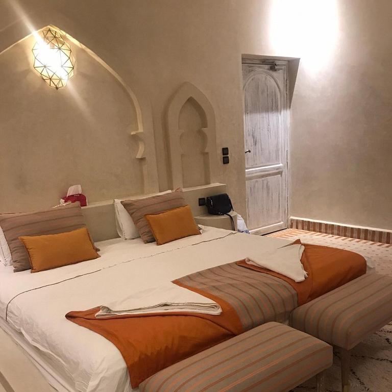 a bedroom with a large bed with orange pillows at Merzouga Hous in Merzouga