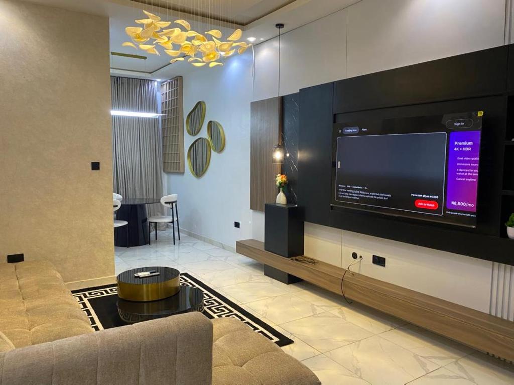 a living room with a couch and a large television at Cozy Corner Apartments in Lekki