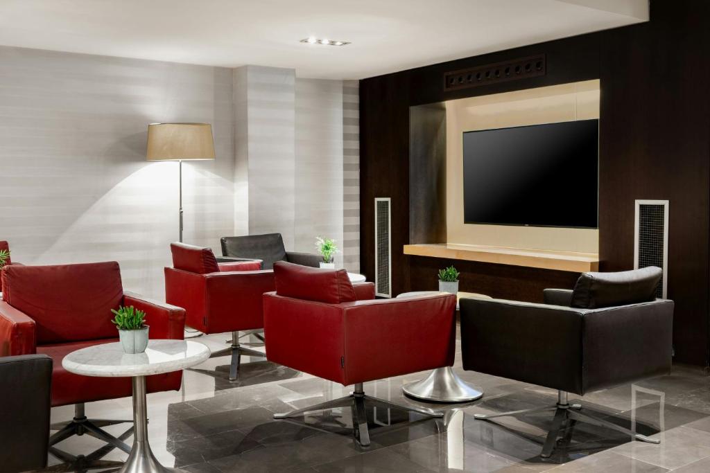 a lobby with red chairs and a flat screen tv at AC Hotel Irla by Marriott in Barcelona
