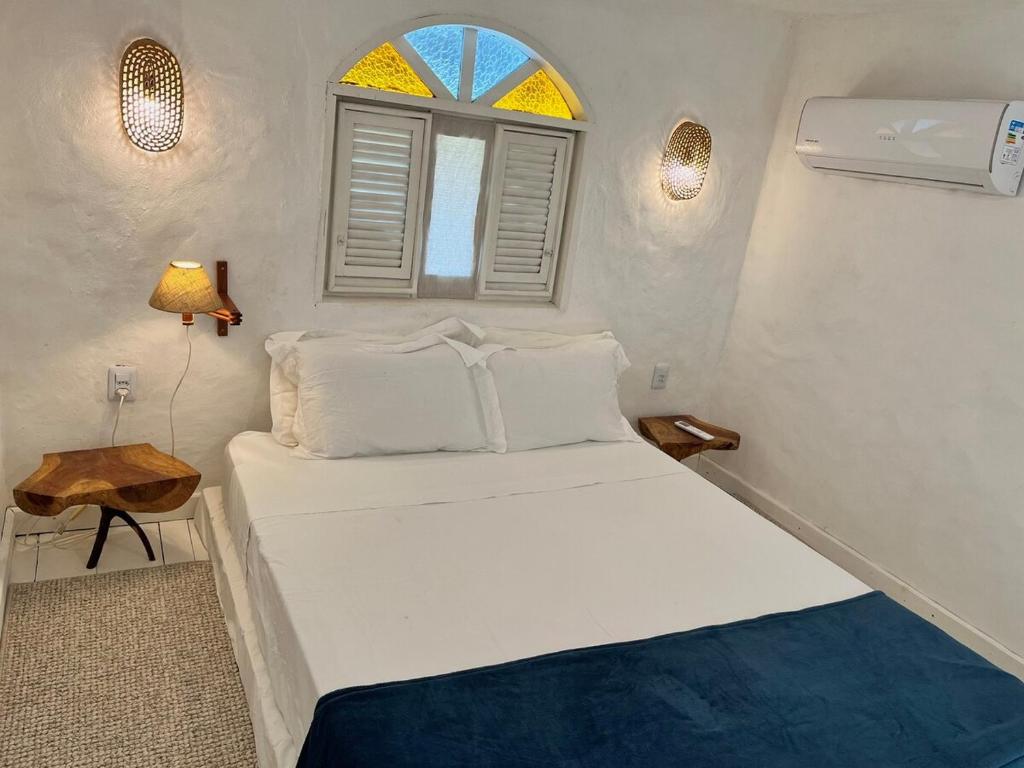 a small bedroom with a white bed and a window at KOA Loft - Praia de Moitas in Amontada