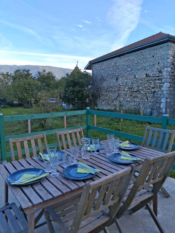 a wooden table with plates and glasses on it at Le Lodge Arthur Appartement 8 personnes in Barraux