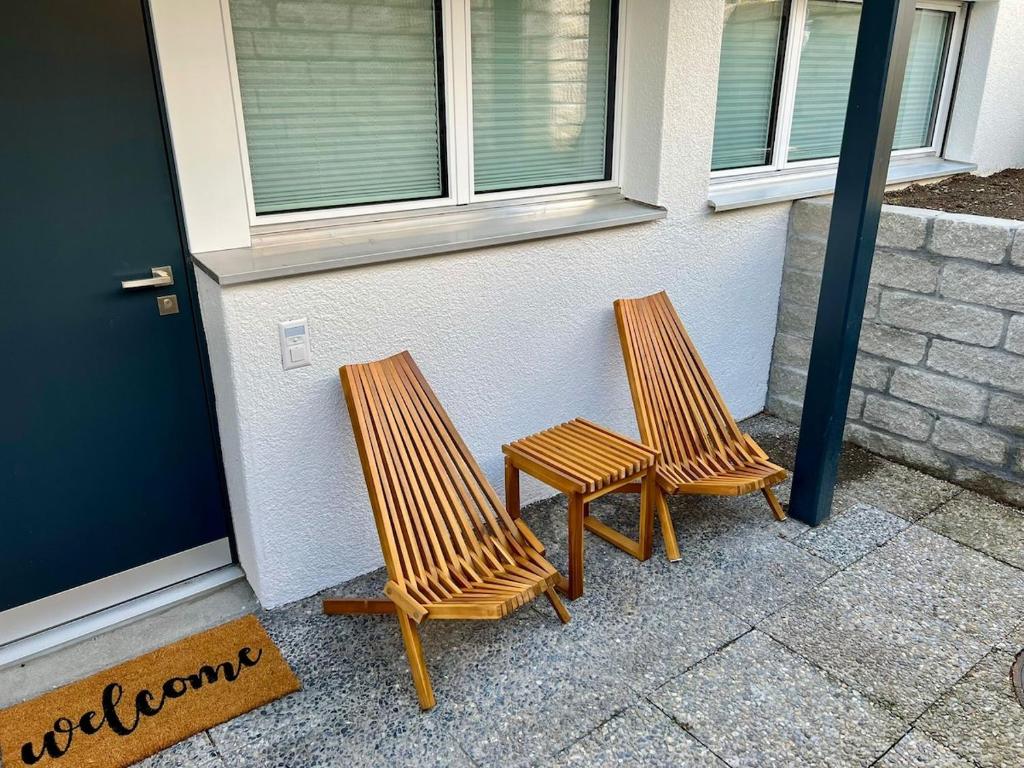 two wooden chairs sitting outside of a building at Gemütliches Studio mit Sitzplatz in Altdorf