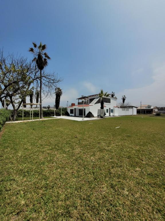 ルリンにあるCasa amplia con Piscina privada y a pasos de la playaの畑のヤシの木がある白い家