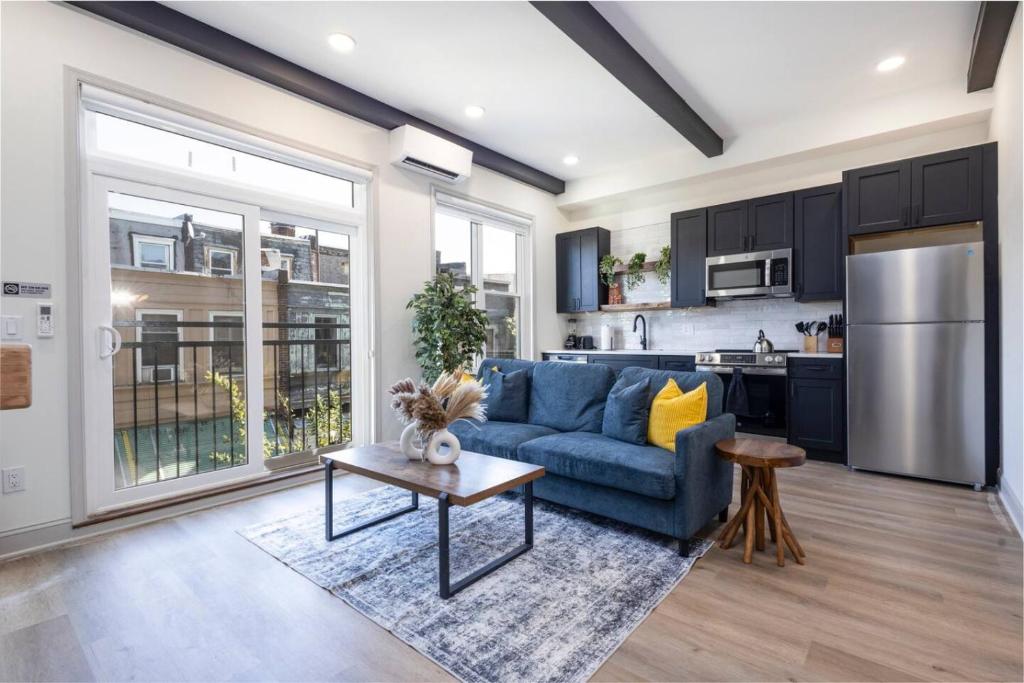 Una sala de estar con un sofá azul y una cocina. en 1BR Across from Fairmount Park - 10 mins to DT (E), en Filadelfia