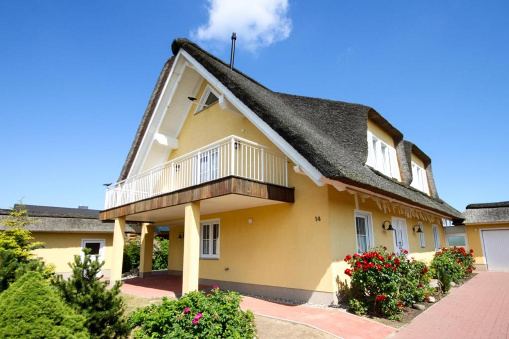 ein gelbes Haus mit schwarzem Dach in der Unterkunft Reetdachhaus "Strandhaus Sterni" in Börgerende-Rethwisch