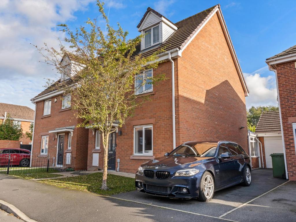 セント・ヘレンズにあるST Helens 5 beds 3bath Fast WIFI Parkingのレンガ造りの家の前に停められた黒車