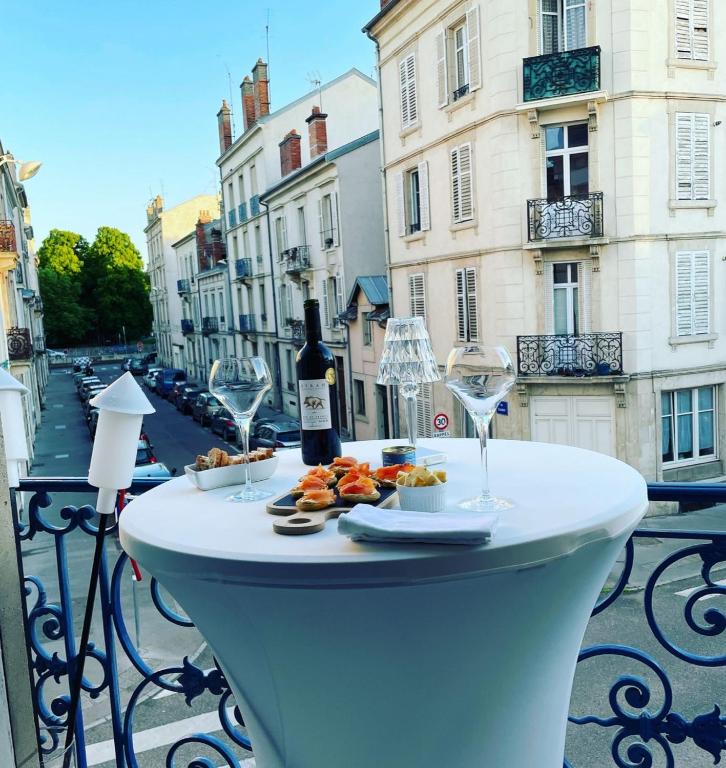 a table with wine glasses and food on a balcony at La suite de la pépinière in Nancy