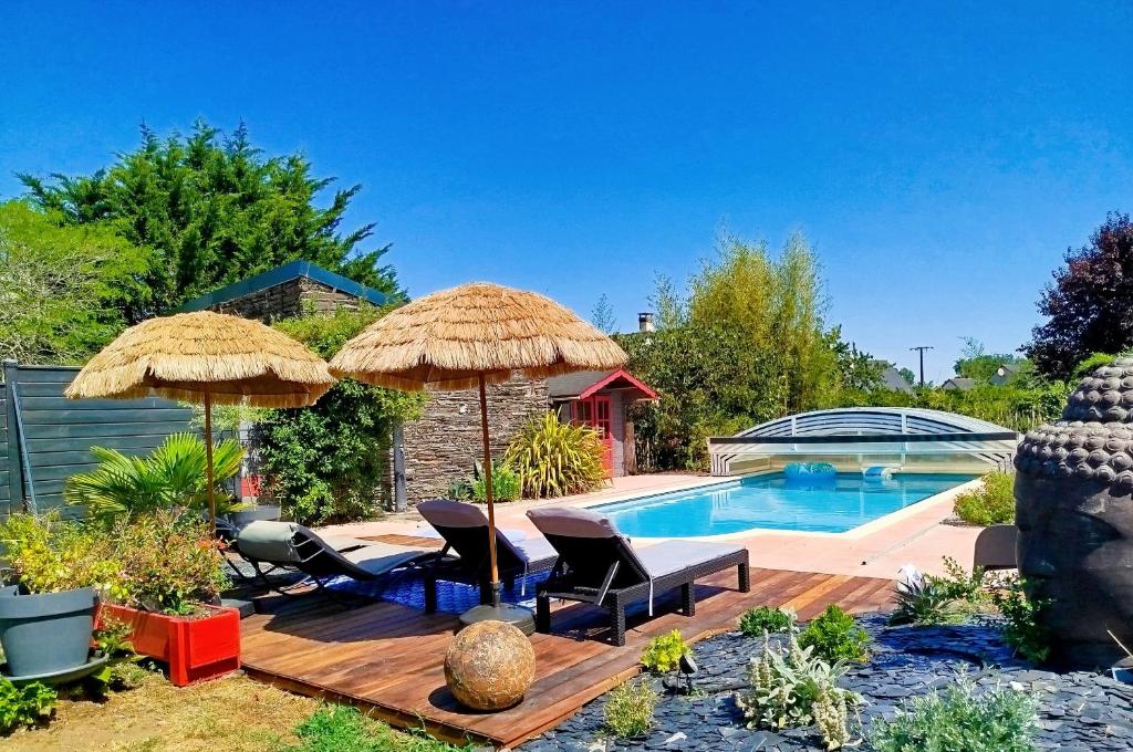 a swimming pool with two umbrellas and chairs and a swimming pool at La maisonnette de Joséphine in Saint-Jean-des-Mauvrets