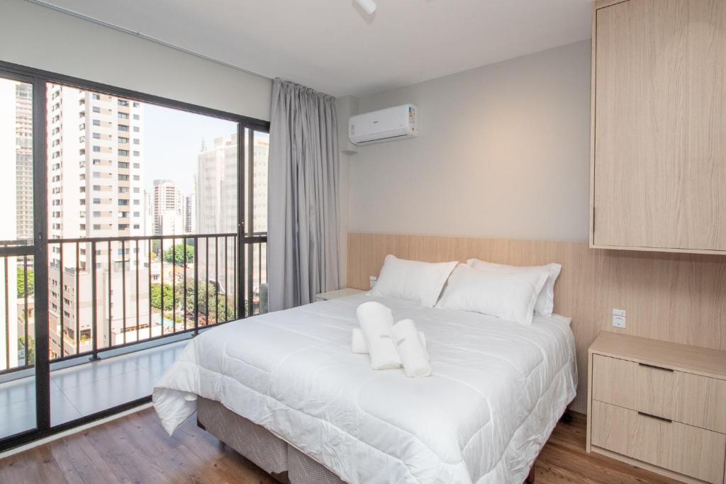 a bedroom with a white bed with a large window at Perdizes Smart Experience - Ao lado do Allianz Parque in Sao Paulo