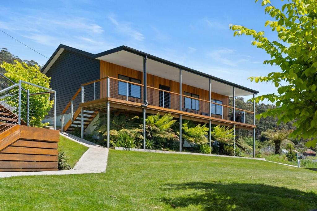 a house with a balcony and a grass yard at The Derby Cabin Stay! NEW HOT TUB! in Derby