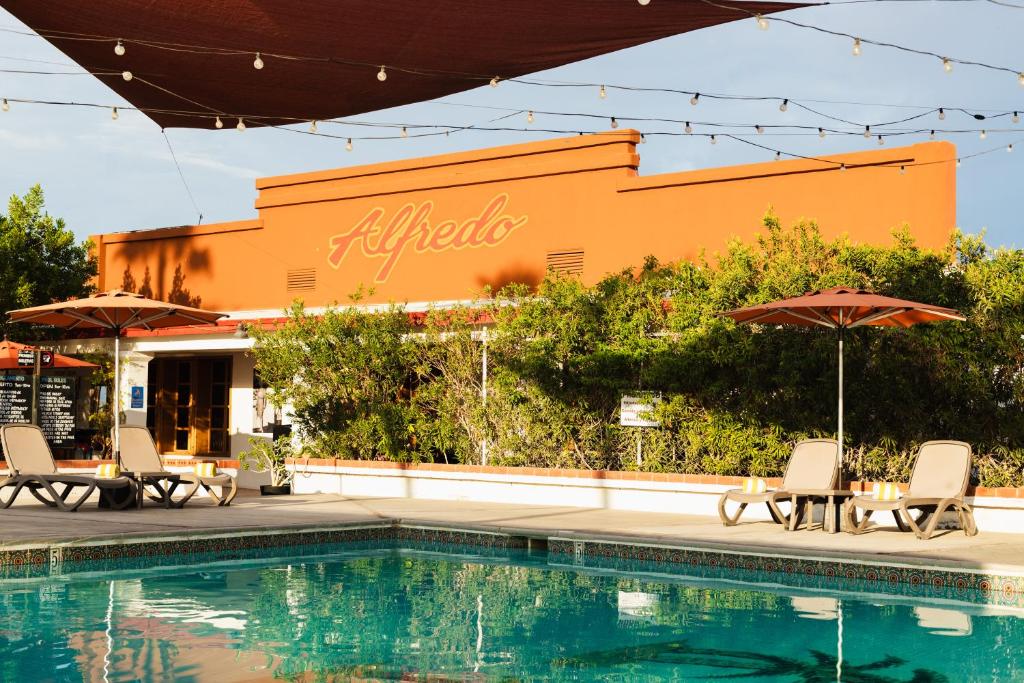 a pool with chairs and umbrellas in front of a building at Hotel Las Palmas in San Felipe