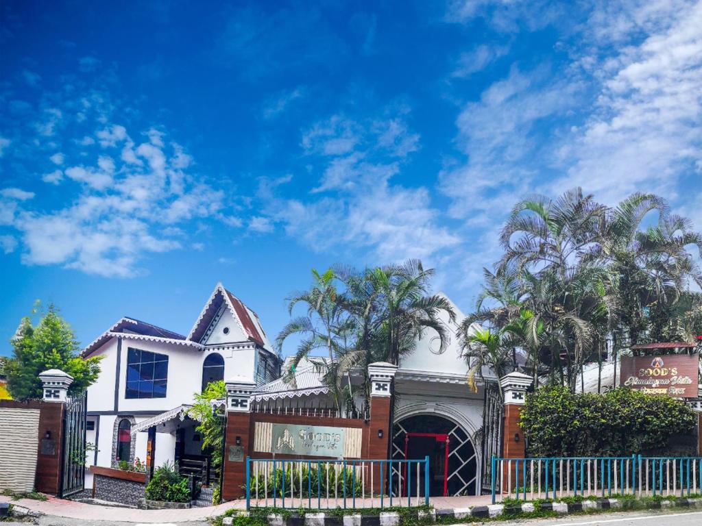 a white house with a fence and palm trees at Sood's Himalayan Vista in Kalimpong