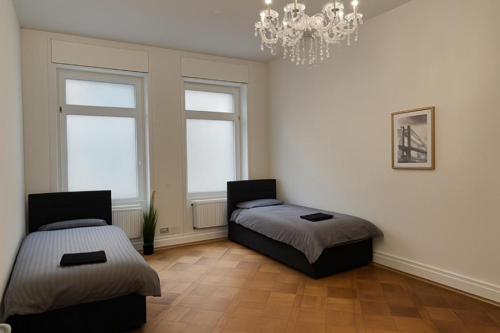 a bedroom with two beds and a chandelier at Offenbach 200 m2 9 Betten O2 EG in Offenbach
