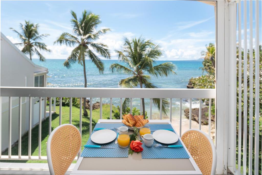a table on a balcony with a view of the ocean at Balcon des alizés pieds dans l'eau in Le Gosier