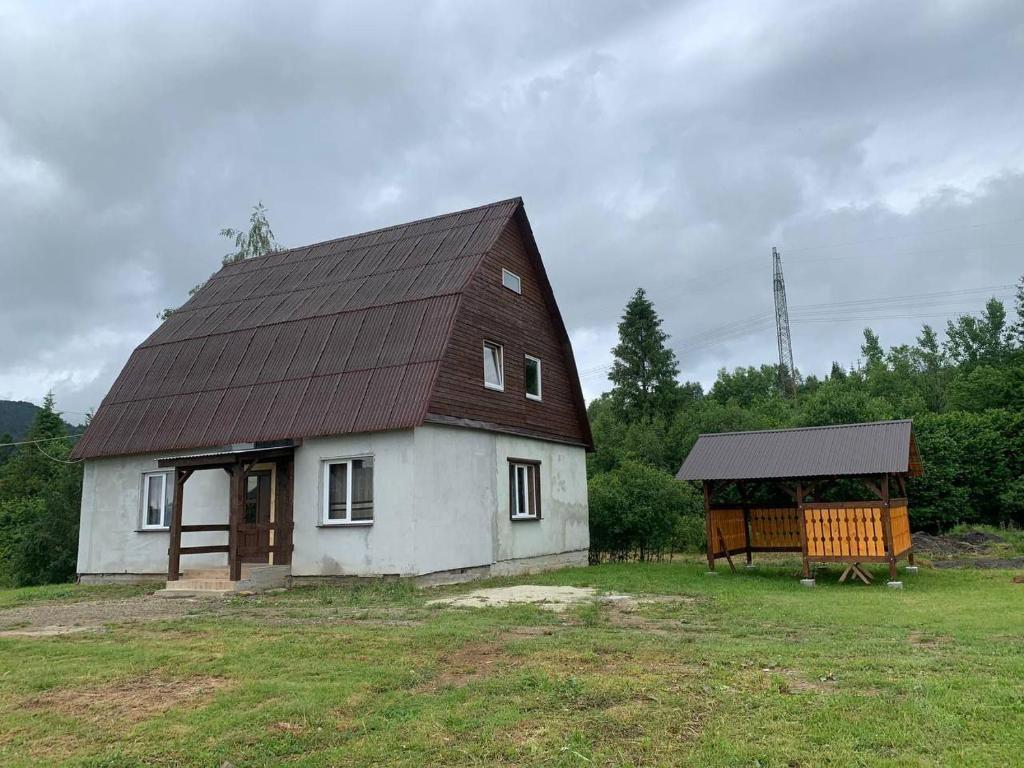 ein kleines weißes Haus mit einem Mansarddach in der Unterkunft Армаден in Slawske