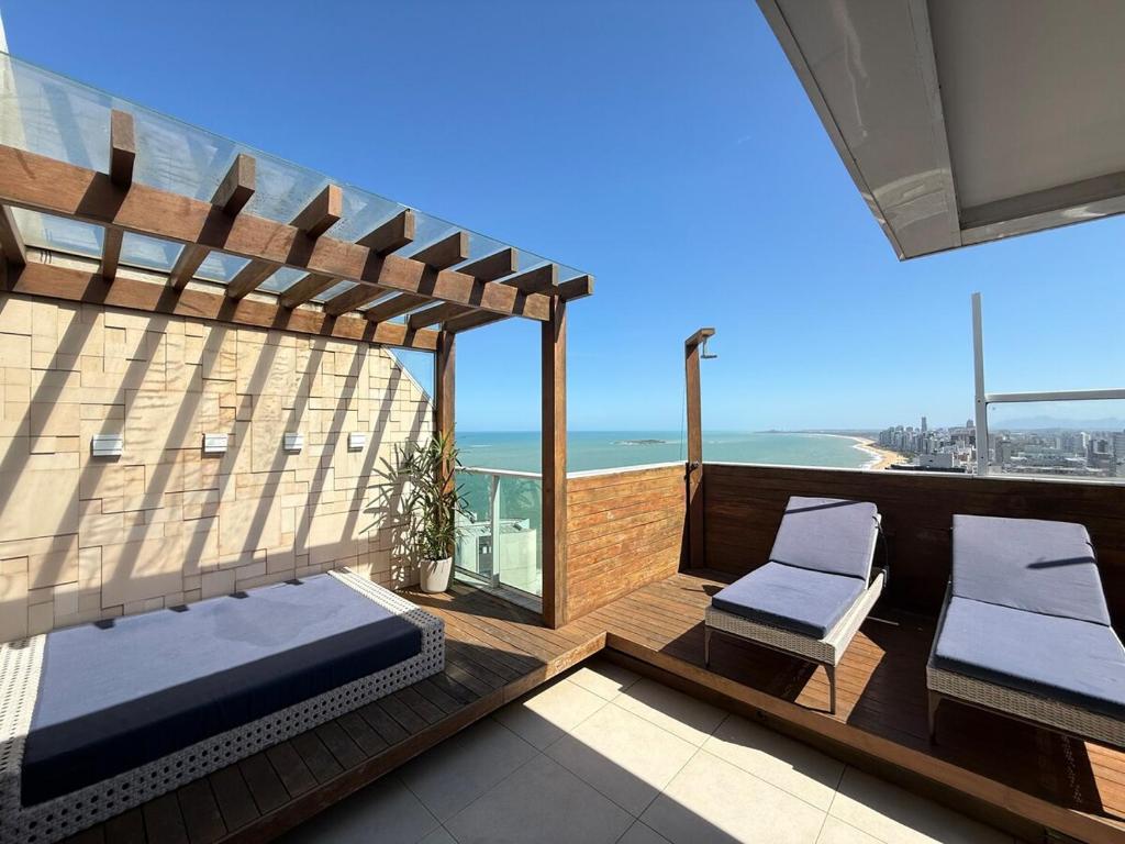 a balcony with two chairs and a view of the ocean at Cobertura dúplex frente mar Sunset in Vila Velha