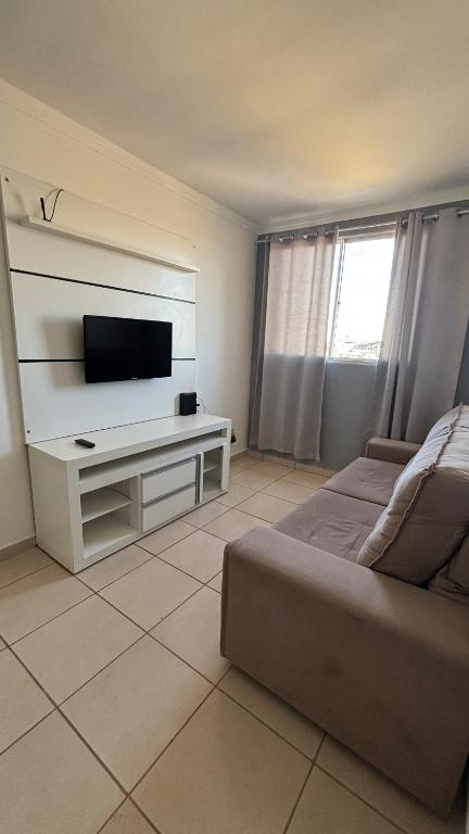 a living room with a couch and a flat screen tv at Apartamento Veneza in Franca