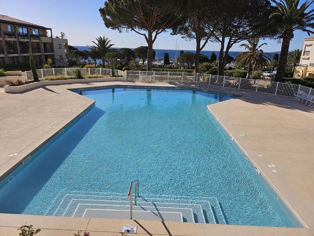 a large blue swimming pool with trees in the background at Ravissant T2 aux Issambres avec Piscine et Climatisation - FR-1-768-126 in La Garonnette-Plage