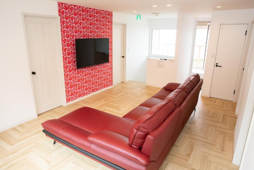 un salon avec un canapé rouge et une télévision dans l'établissement Free Car Parking コスモブラン Cosmos blanc CB1, à Otaru
