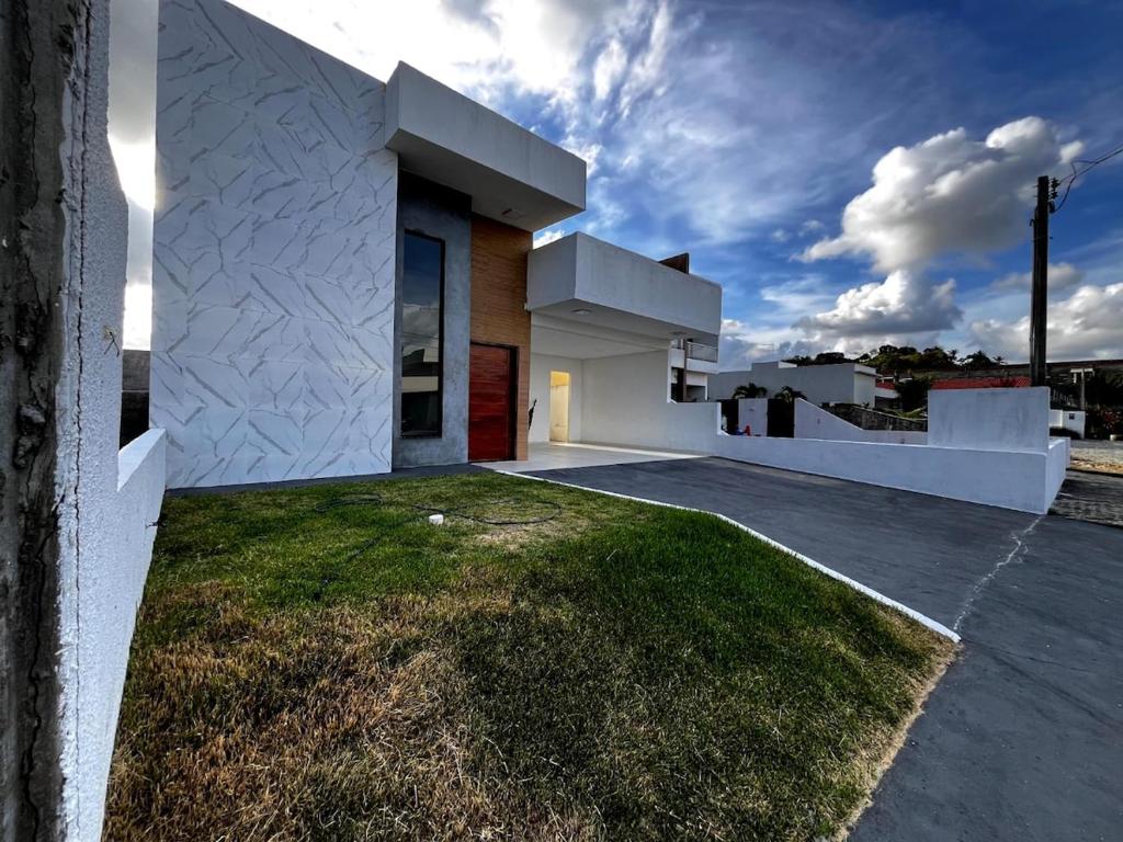 a white house with a grassy yard at Casa de condomínio em Paripueira in Paripueira