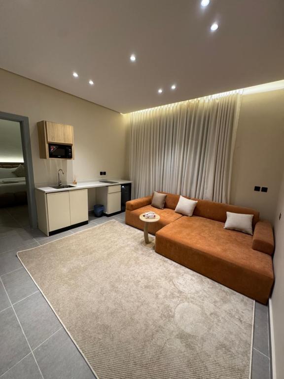 a living room with a brown couch and a kitchen at Luxury studio in Al-ʿUla