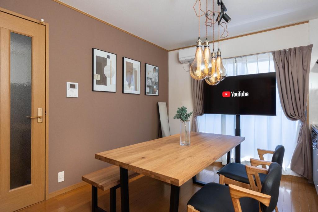 una sala da pranzo con tavolo e sedie in legno di Maison Raffine ad Osaka