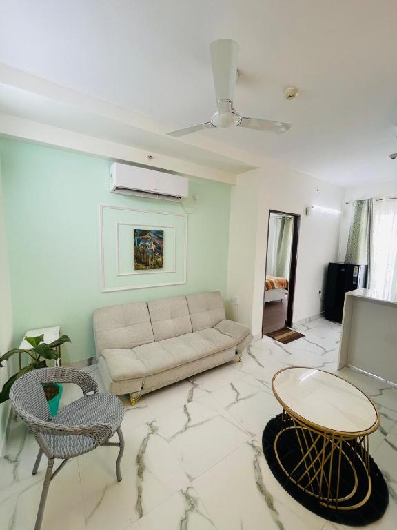 グルガオンにあるWhite Grass3 Cozy Apt in Gurgaonのソファとテーブルと椅子のあるリビングルーム
