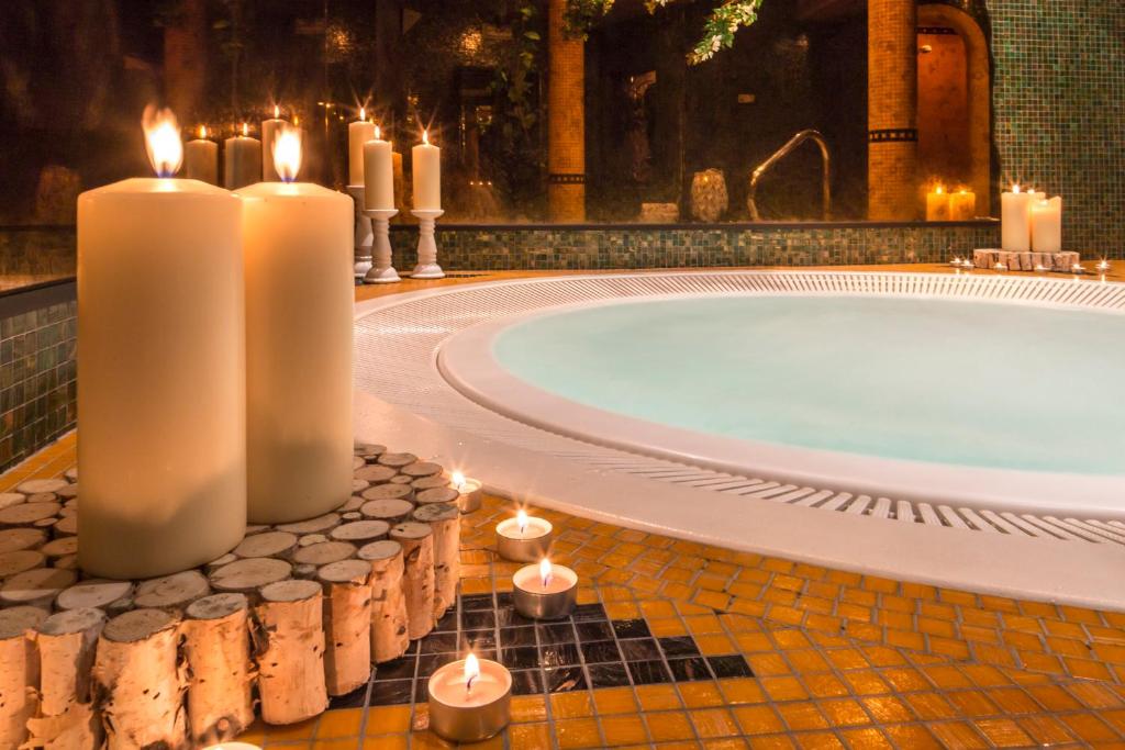 uma casa de banho com velas e uma banheira com uma banheira. em Hotel Chalet Olympia em Monguelfo