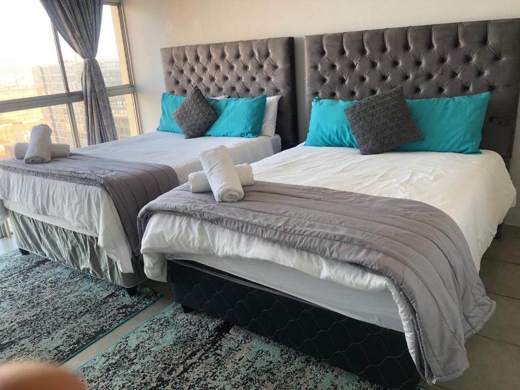 Un dormitorio con dos camas con almohadas azules. en T' Primage Suite on Ten South, en Durban