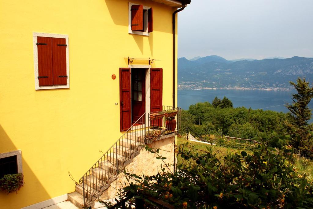 żółty dom z czerwonymi drzwiami i balkonem w obiekcie Villa Marilena w mieście San Zeno di Montagna