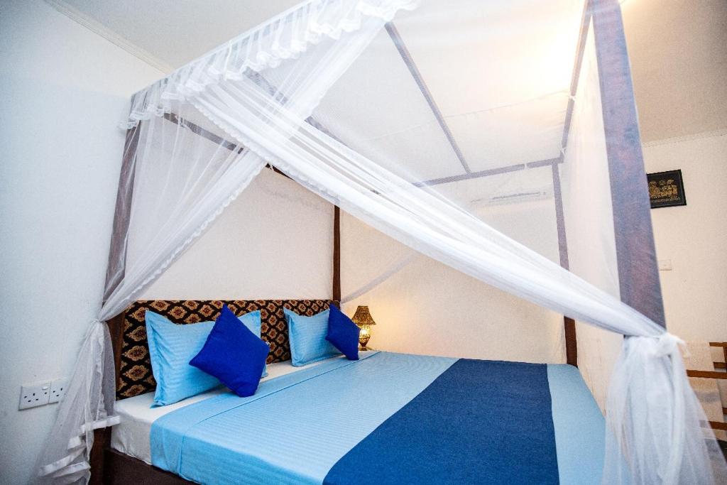 una camera con letto a baldacchino e cuscini blu di Susu Eco Villa a Talpe