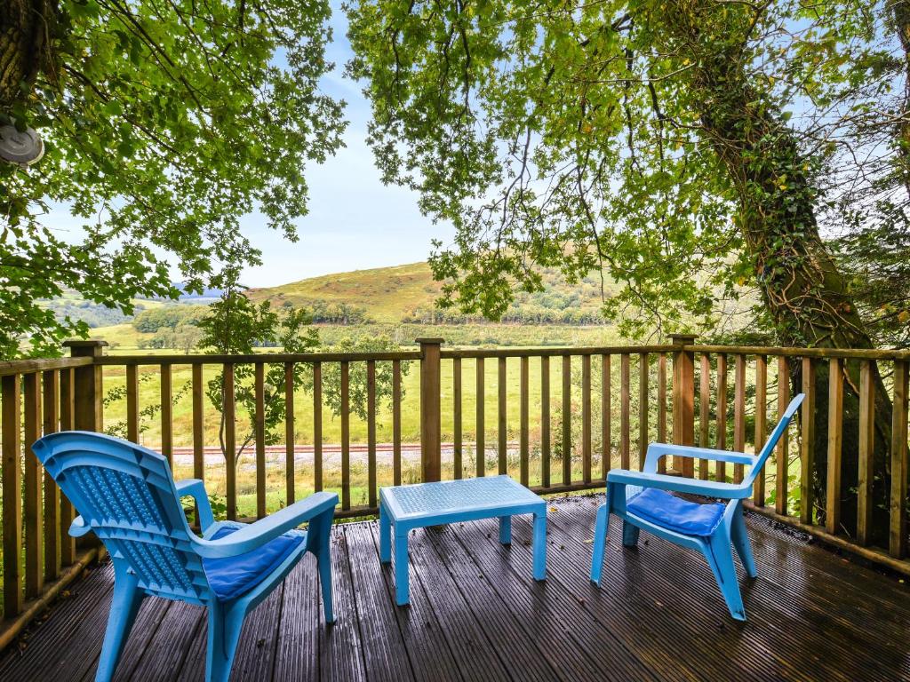 two blue chairs and a table on a deck at The Owl's Nest - Uk50546 in Penegoes