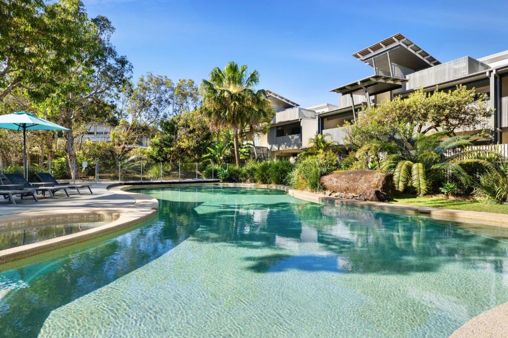 a swimming pool with blue water in a resort at East On Byron Bay Apartments in Byron Bay