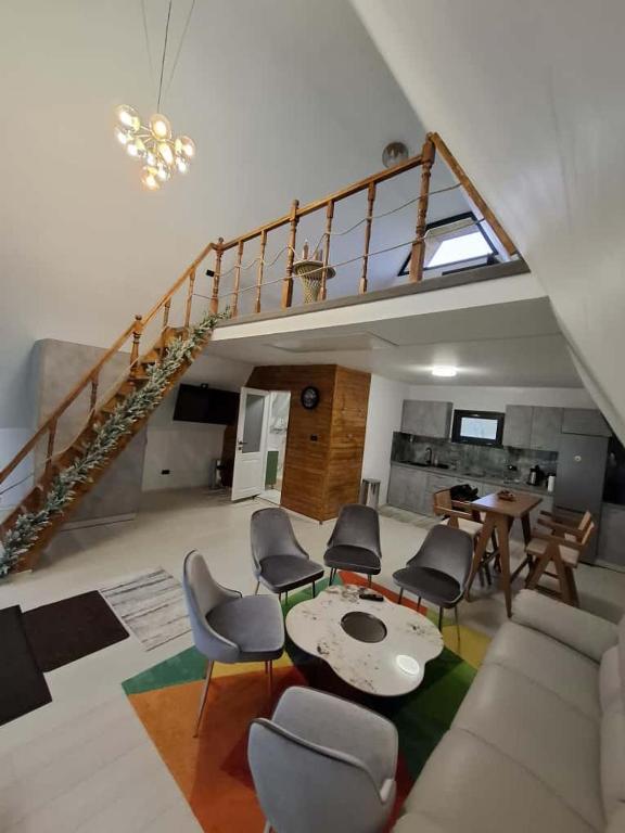 a living room with a staircase with chairs and a table at Aframe Lac Malei in Petrila