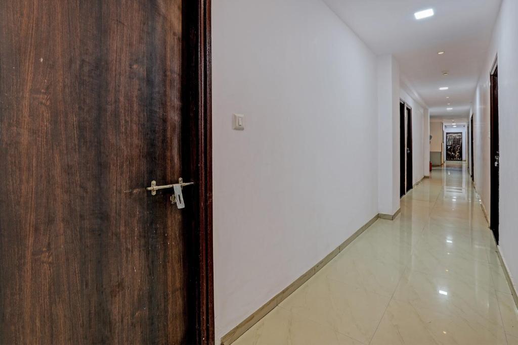 a hallway with a wooden door and a hallway with white walls at Hotel O Royal Inn in Ahmedabad