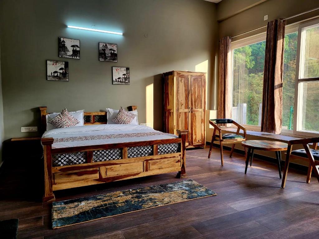 a bedroom with a bed and a table and a window at Alchemy Bistro and Inn, Dharamshala in Dharmsala