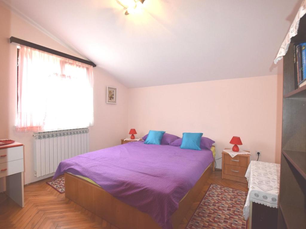 a bedroom with a purple bed and a window at Comfortable holiday home only 500m to the sea with outdoor kitchen, wifi and airco in Banjole